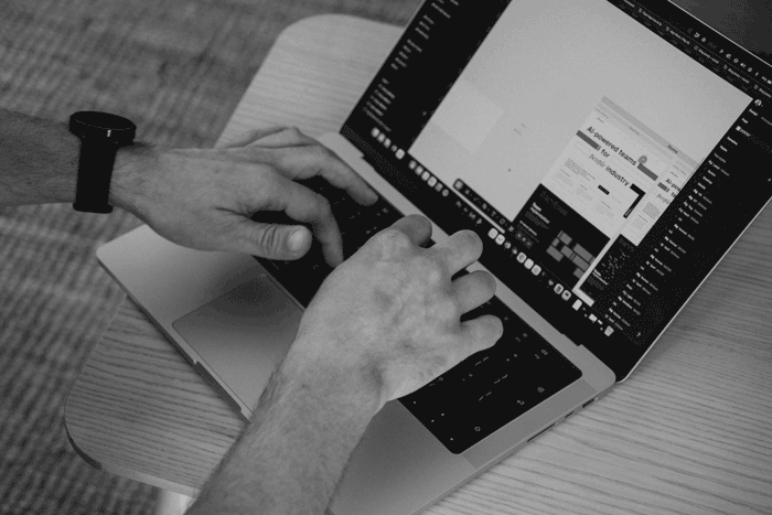 Hands typing on a laptop with a design tool open